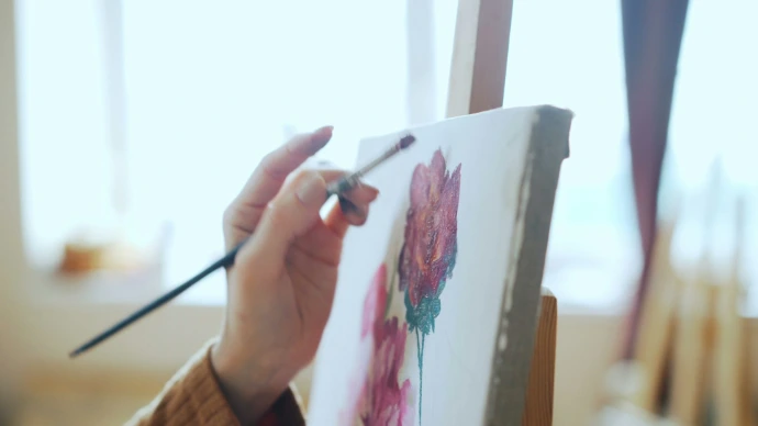 An artist paints a floral picture.